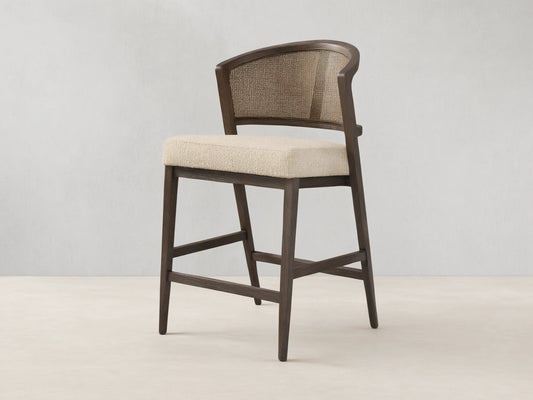 Aimee Armless Counter Stool with solid oak frame, rattan cane back, and upholstered seat. Hand-finished wood with lacquer.