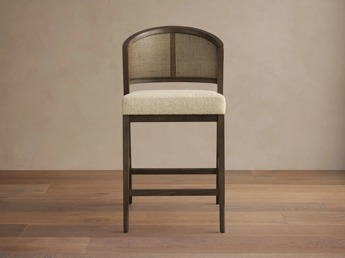 Aimee Armless Counter Stool with solid oak frame, rattan cane back, and upholstered seat. Hand-finished wood with lacquer.