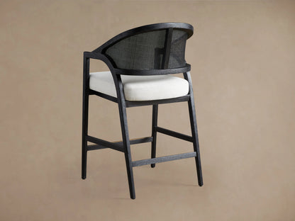 Aimee Stool in Black Drifted finish showing curved, rattan cane backrest with black frame, and a cream upholstered seat.