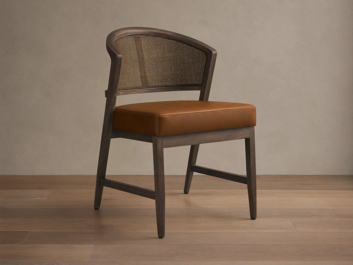 Front angled view of the Black Drifted Aimee Faux Leather Dining Side Chair with a rattan cane back and brown faux leather seat.