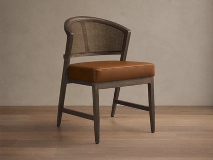 Front angled view of the Black Drifted Aimee Faux Leather Dining Side Chair with a rattan cane back and brown faux leather seat.