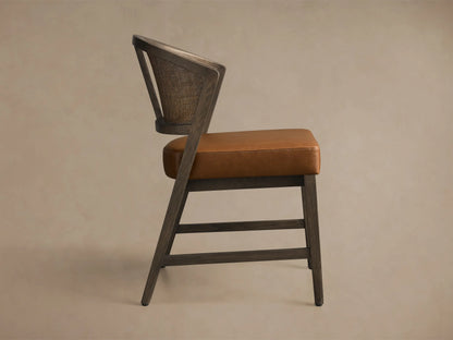 Side view of the Aimee Faux Leather Dining Side Chair with dark wood frame, brown faux leather seat, and rattan cane back.