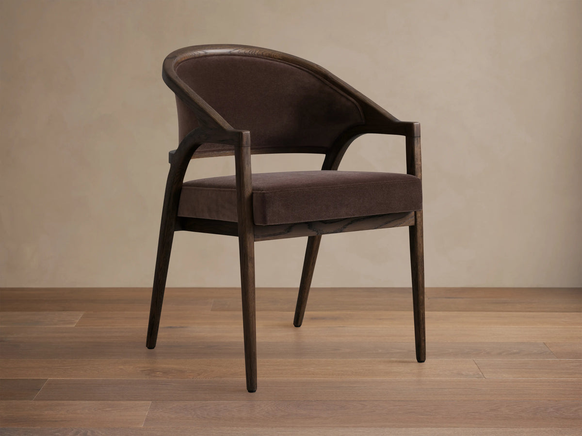 Aimee Upholstered Back Dining Arm Chair in dark brown fabric with solid oak frame, curved back, and cushioned seat on wooden floor.
