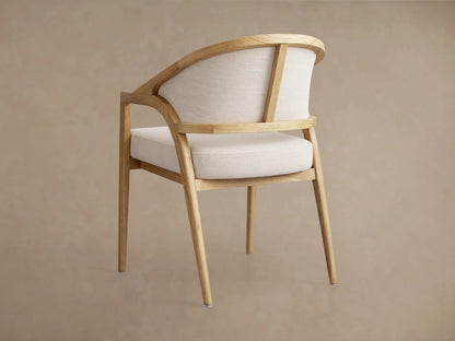 A close-up of the Aimee Upholstered Back Dining Arm Chair, showcasing light oak wood frame and beige upholstered back and seat.