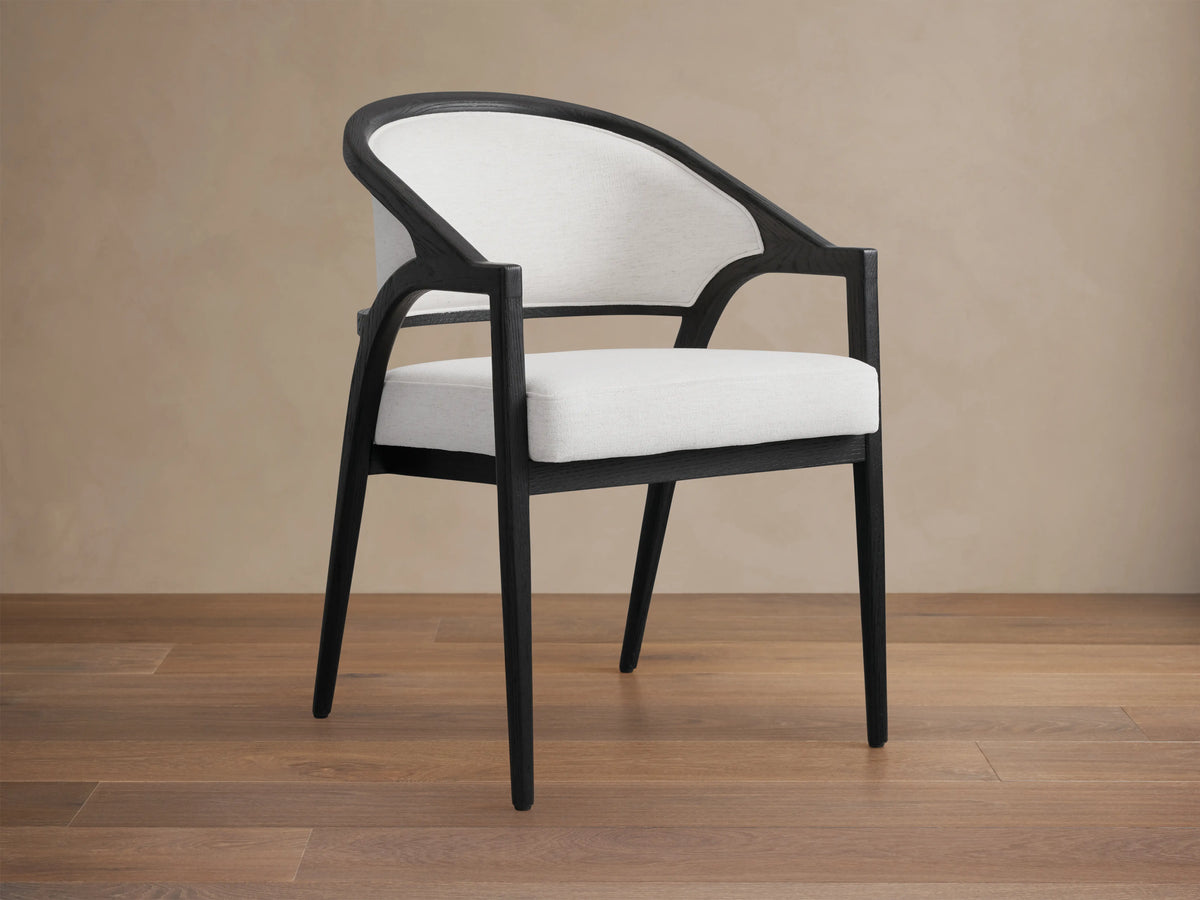 Aimee Upholstered Back Dining Arm Chair with a black solid oak frame, curved back, and light fabric upholstery, viewed from the back.