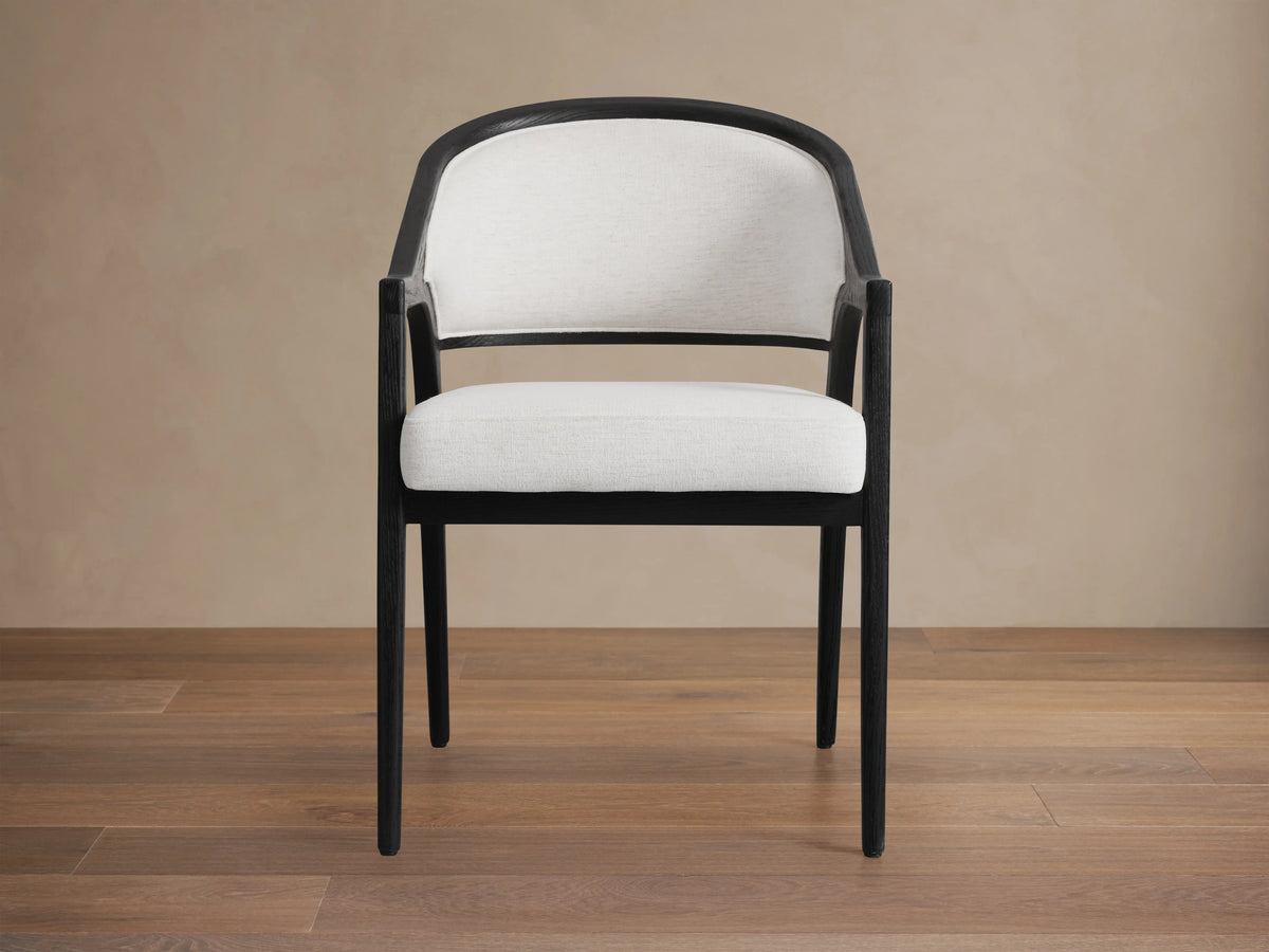 Aimee Upholstered Back Dining Arm Chair with a dark oak frame, white upholstered back and seat, on a wooden floor.