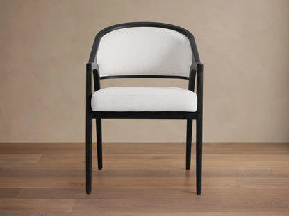 Aimee Upholstered Back Dining Arm Chair with a dark oak frame, white upholstered back and seat, on a wooden floor.