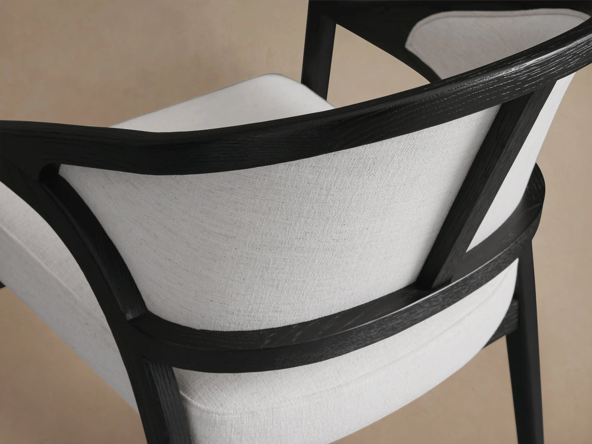 Aimee Upholstered Back Dining Arm Chair with solid oak frame, black lacquer finish, white upholstered back and seat, on wood floor.