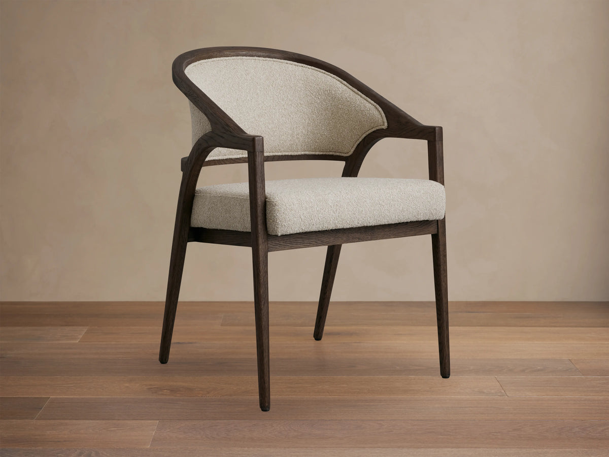 Aimee Upholstered Back Dining Arm Chair with curved dark oak frame, light beige fabric seat and back, shown from rear angle.