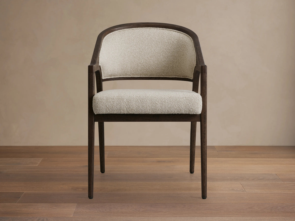 Aimee Dining Arm Chair with upholstered cream back and seat, solid oak frame in dark brown, on a wooden floor.