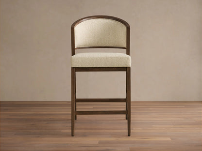 Aimee Upholstered Back Armless Counter Stool with a cream upholstered seat and back, solid oak frame, on a wooden floor.