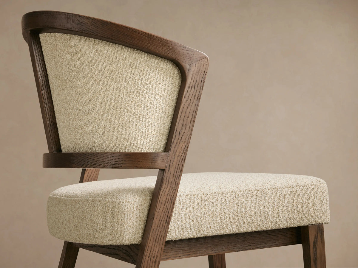 Aimee Upholstered Back Armless Counter Stool with solid oak frame, beige fabric seat and back, on wood floor, neutral backdrop.