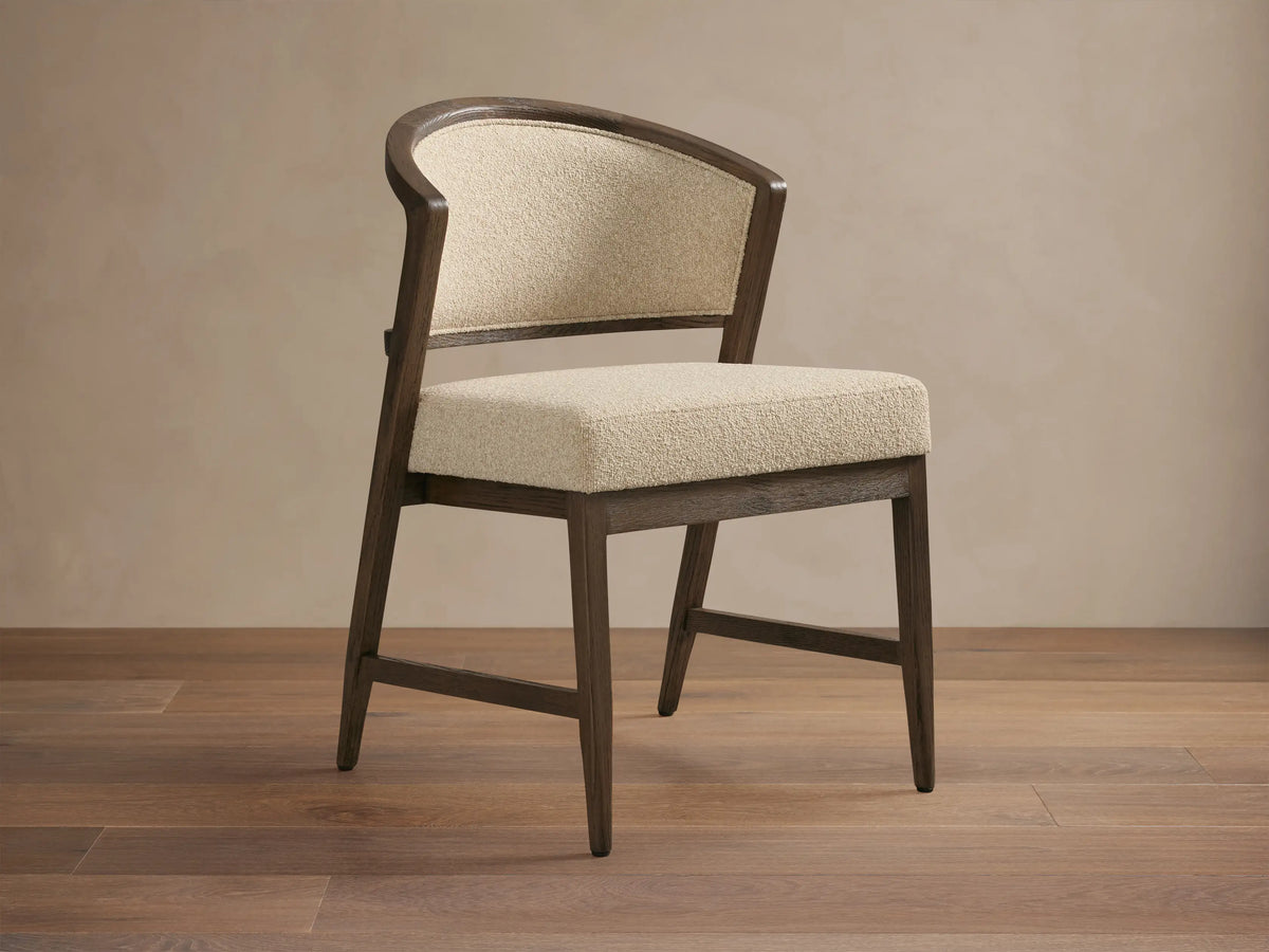 Aimee Upholstered Back Dining Side Chair with dark wood frame, beige cushioned seat and backrest, set on a wooden floor.
