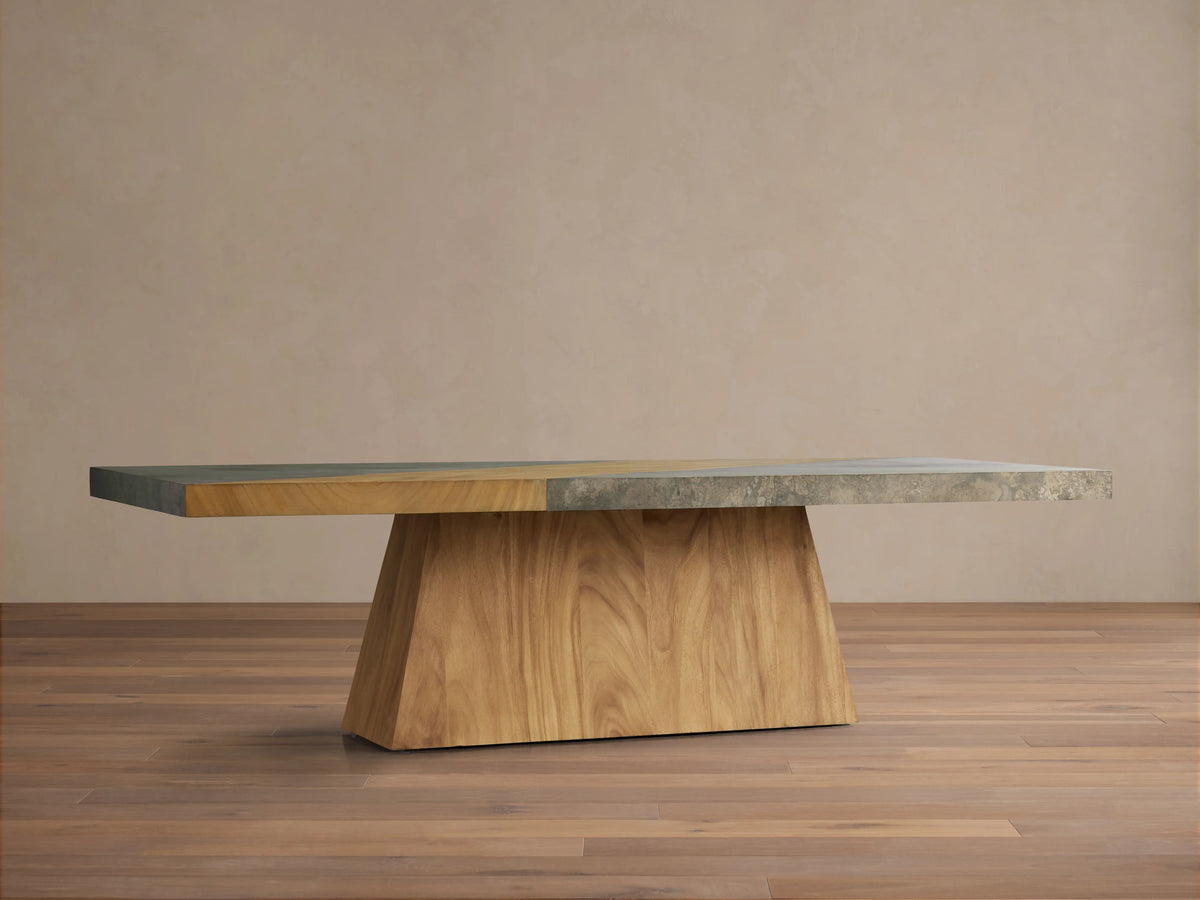 Almeria Dining Table with a guanacaste wood base and oxidized steel top, showing a distinct distressed patina on wooden floor.