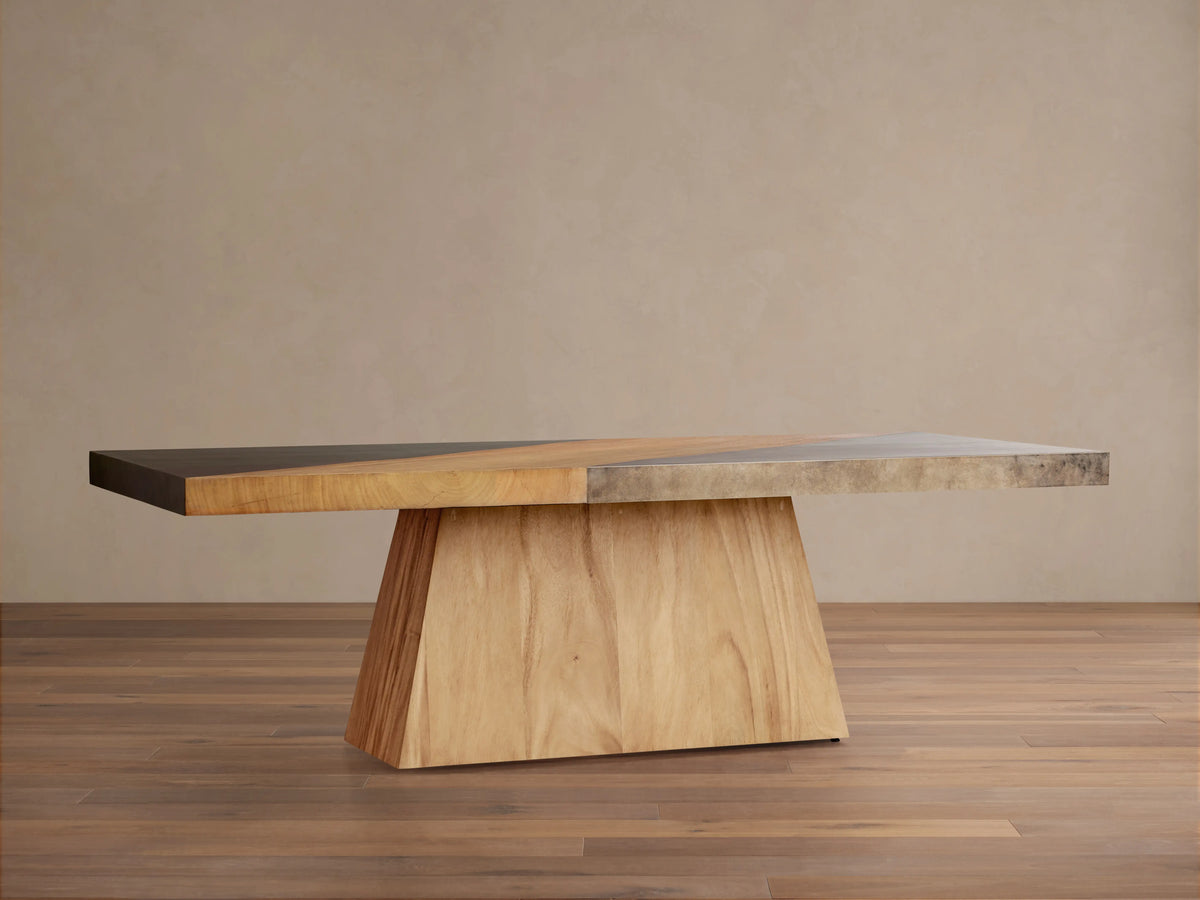 Almeria Dining Table made of guanacaste wood and oxidized steel, rectangular top with unique patinas, on a tapered wooden base.