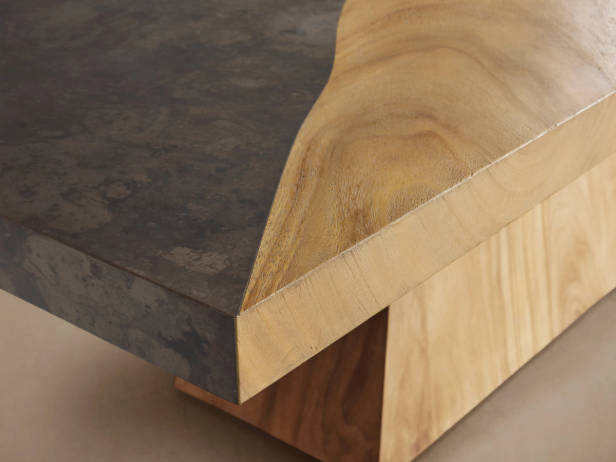 Almeria Dining Table with a thick, rectangular guanacaste wood top and oxidized steel panel on a trapezoidal wooden base.