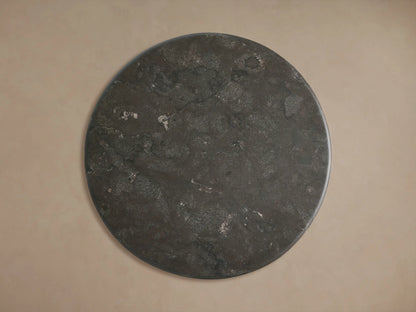 Amelia Bistro Table: Dark bluestone round top, dark oak grain pedestal base, close-up, angled against a beige wall.
