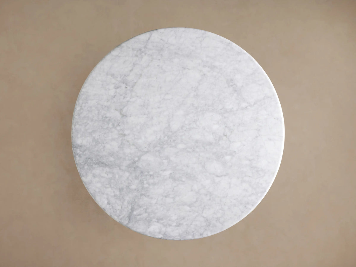 Close-up of Amelia Dining Table: white Carrara marble top with grey veining, light natural oak wood sculptural pedestal base.