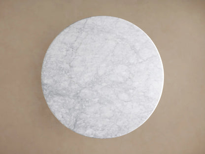 Close-up of Amelia Dining Table: white Carrara marble top with grey veining, light natural oak wood sculptural pedestal base.