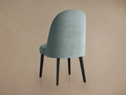 Arco Channel Dining Chair with a light blue cushioned seat and backrest featuring elegant channel detailing. Supports are dark wood.