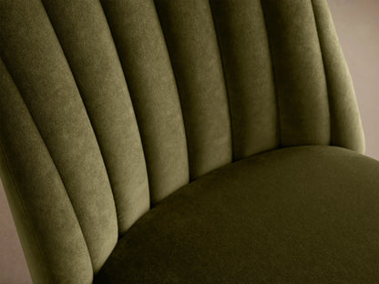 Frontal view: Arco Channel Dining Chair in olive green velvet with vertical channel tufting on the backrest, black legs, on a wooden floor.