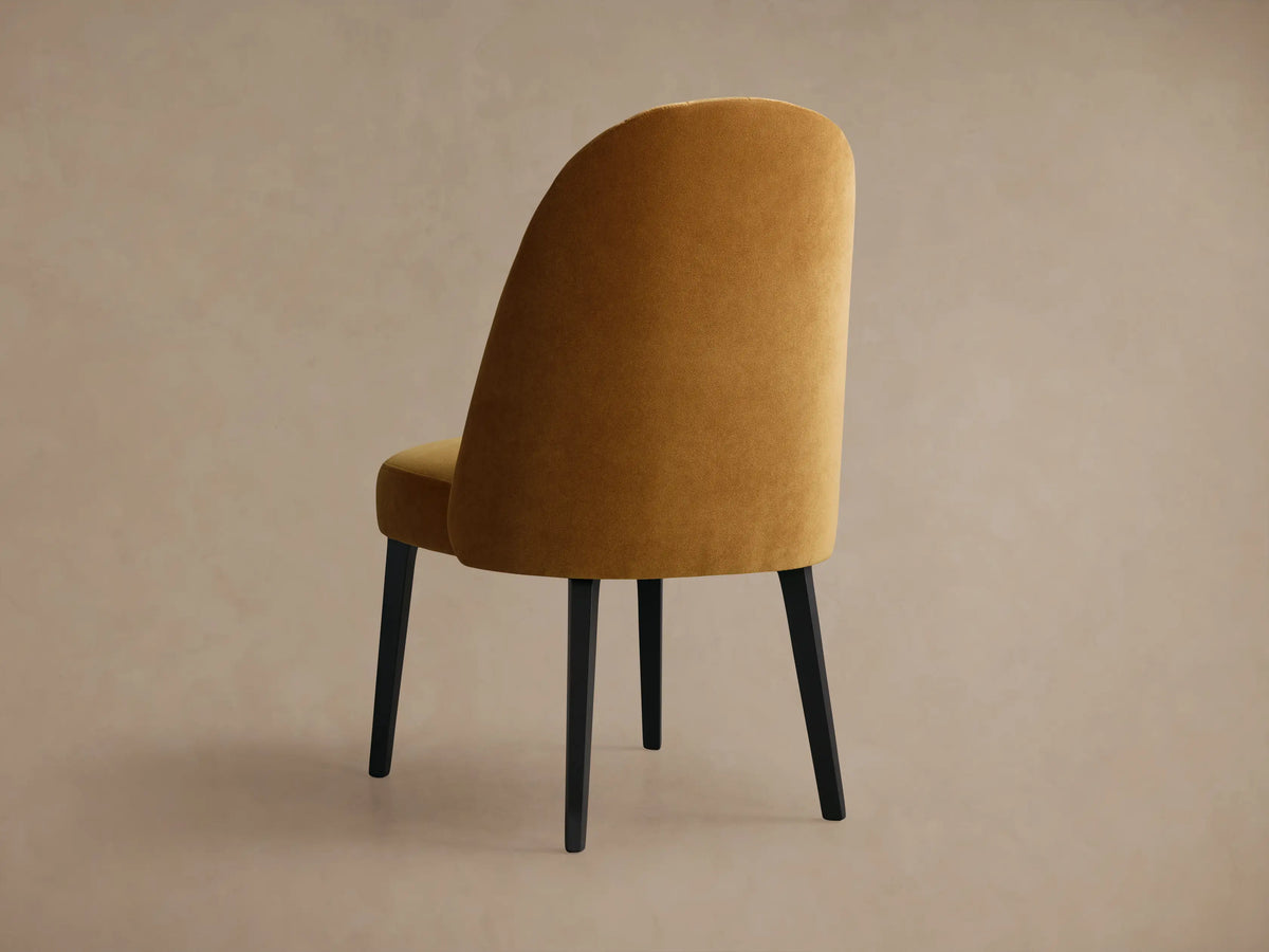 Close-up of Arco Channel Dining Chair's backrest, featuring plush, golden-brown fabric with elegant channel detailing.