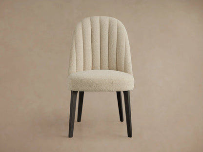 Arco Channel Dining Chair, cream boucle fabric with a curved channel-tufted backrest and dark wood legs, angled right.