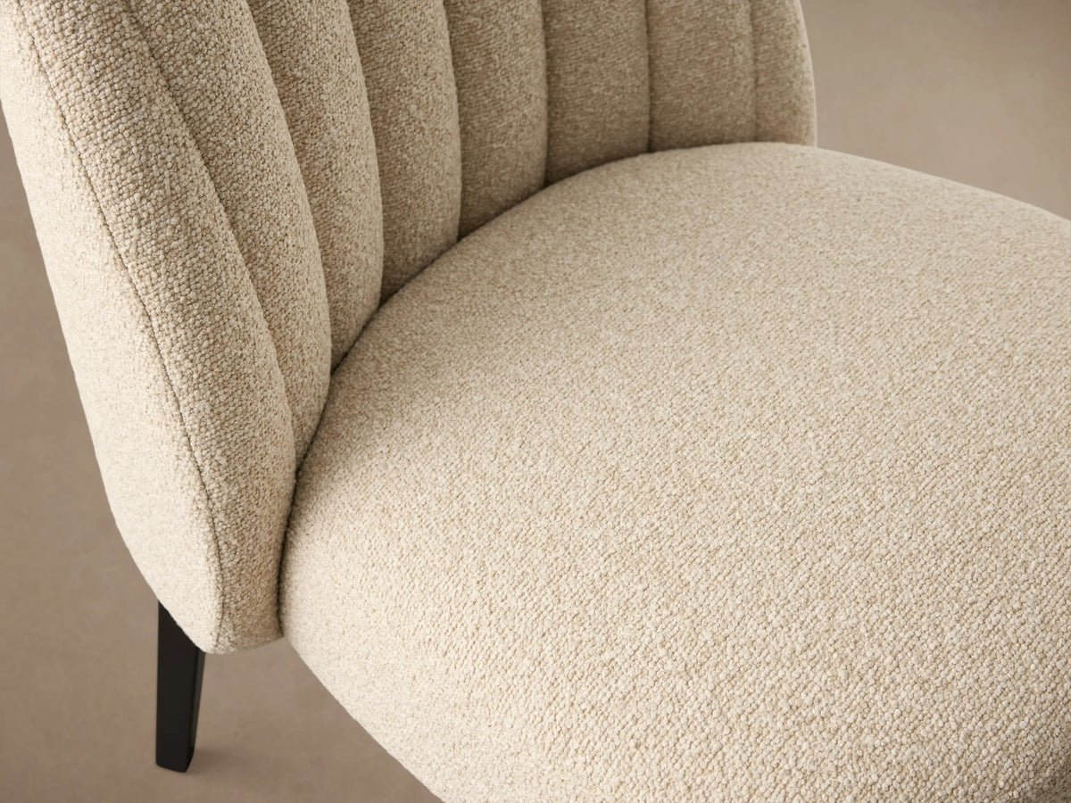 Arco Channel Dining Chair with textured cream upholstery, rounded backrest, elegant vertical channels, and dark tapered legs.