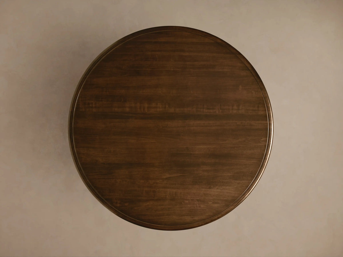 Round Asolo Dining Table with dark wood finish, hand-carved curvaceous pedestal, and subtle distressed detailing.