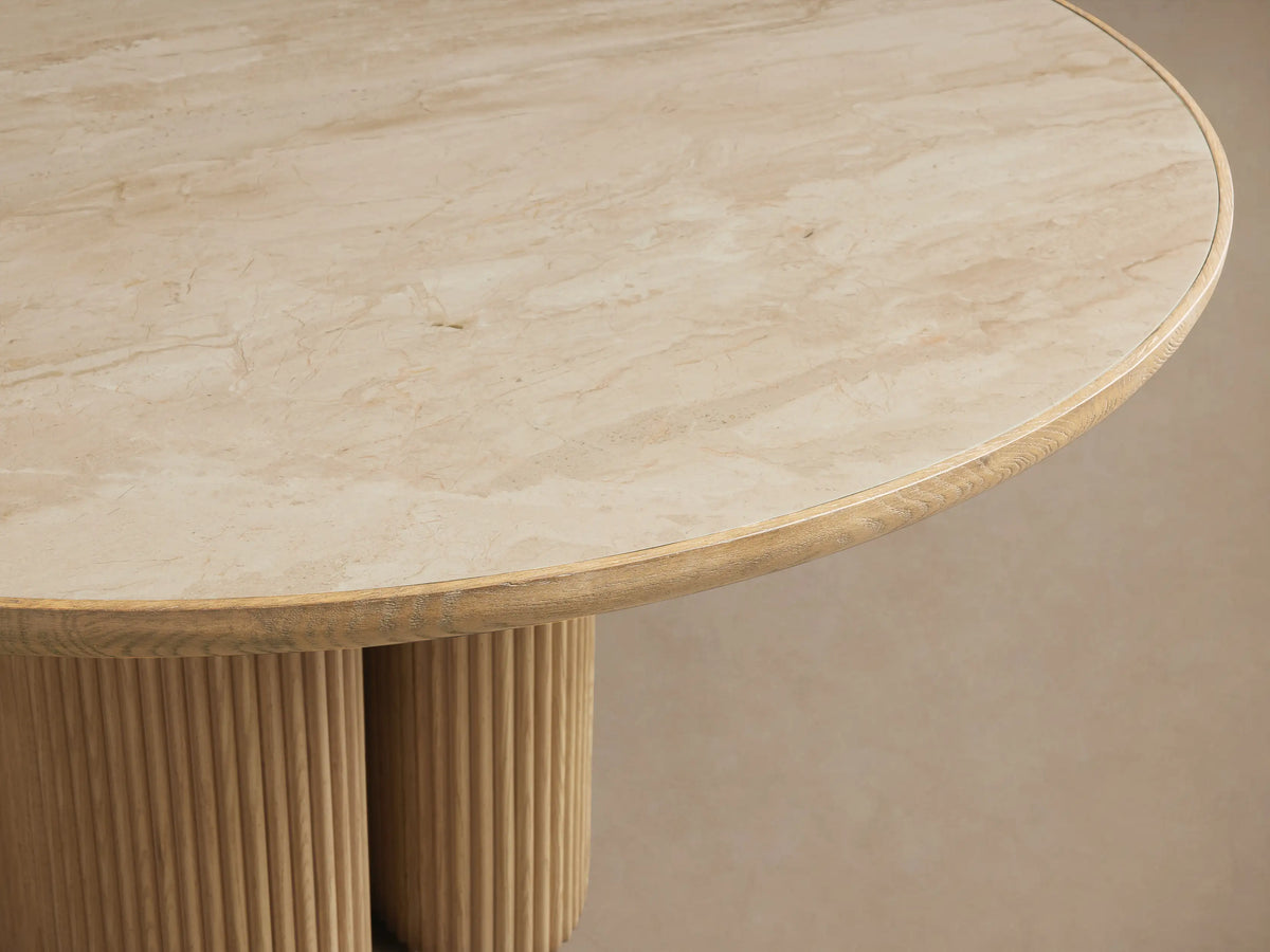 Astor Round Dining Table. Light oak wood, round top, and twin reeded cylindrical pedestal base on a wood floor.