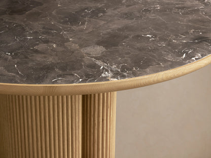 Astor Round Dining Table with oak veneer base and solid reeding, featuring an inset natural marble stone top on wooden floor.