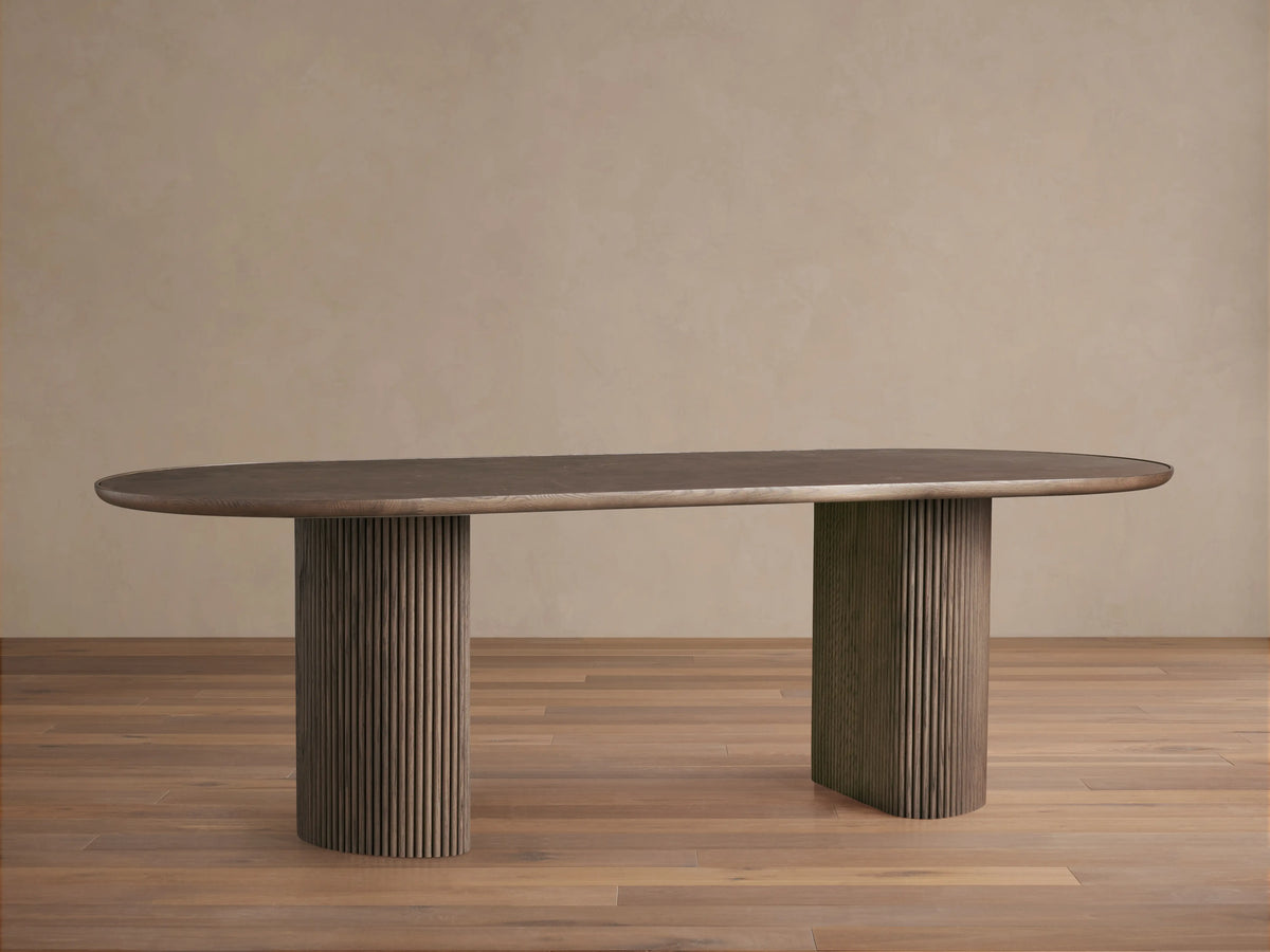 Astor Dining Table with oval brown marble top featuring intricate white veining, set against a neutral background.