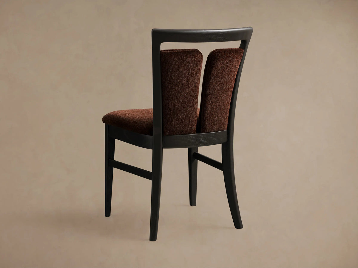 Close-up of the rust brown upholstered Beatrice Dining Side Chair, showing its dark wood split-back frame, angled.