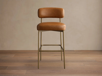 Front view of a brown leather bar stool with a padded seat and back, on a slim gold metal frame with a square footrest.