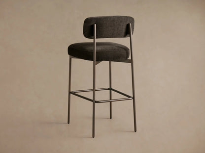 Close-up of Billie Stool's dark grey textured fabric seat and curved backrest, with a dark antiqued iron frame.