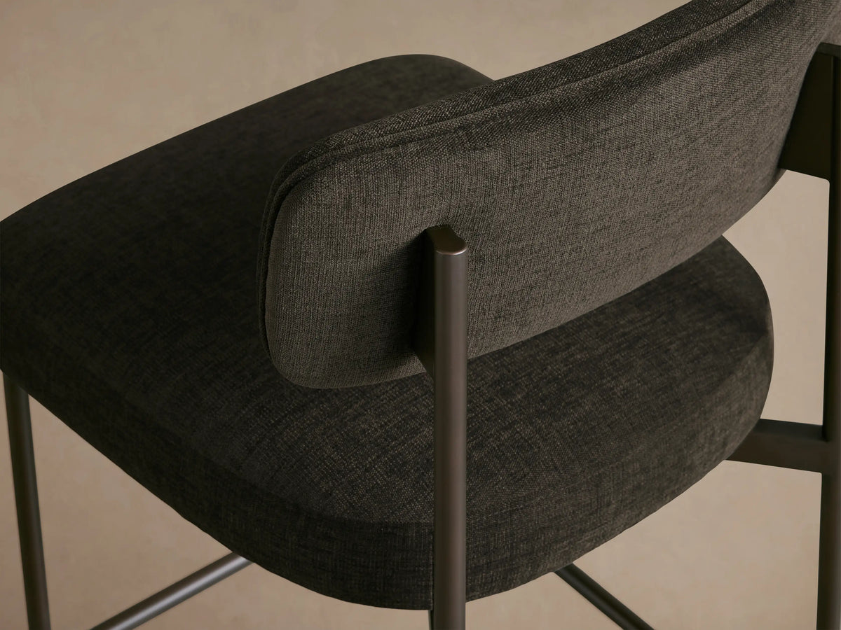 Billie Stool, dark gray upholstered seat and back, antiqued dark bronze metal frame, facing forward.
