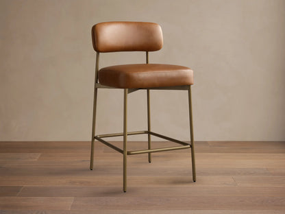 Front view of the brown Billie Stool in Faux Leather, featuring a padded seat and backrest, on an antiqued iron frame.