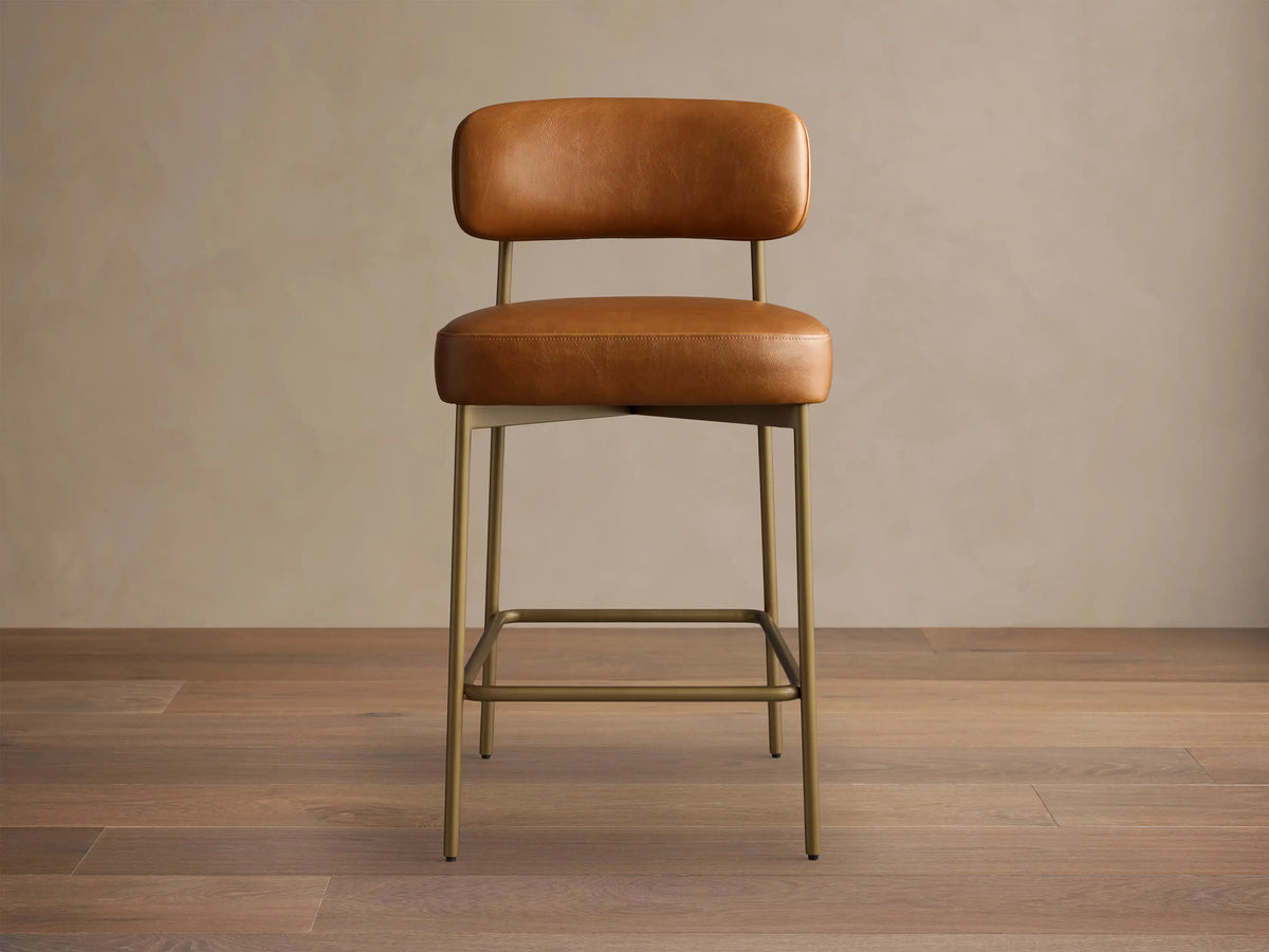 Front view of the brown Billie Stool in Faux Leather, featuring a padded seat and backrest, on an antiqued iron frame.