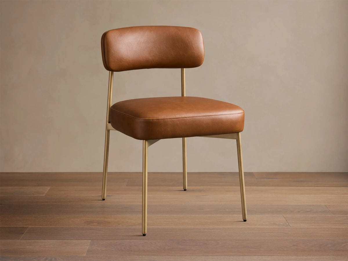 Front view of the brown faux leather Billie Dining Chair with gold-toned metal legs and a padded seat.