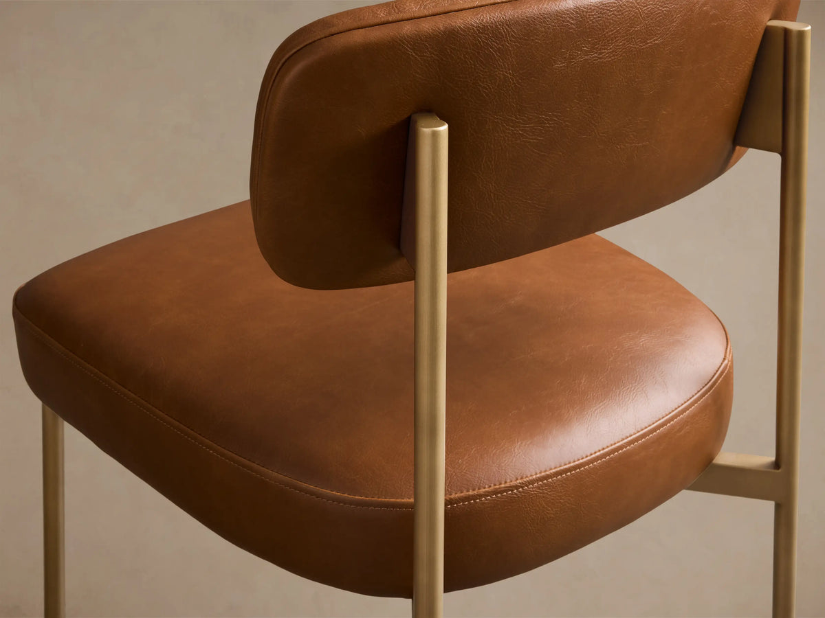 Front view of the brown faux leather Billie Dining Chair with gold-toned metal legs and a padded seat.