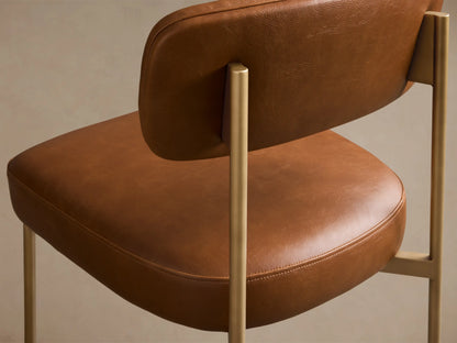 Front view of the brown faux leather Billie Dining Chair with gold-toned metal legs and a padded seat.