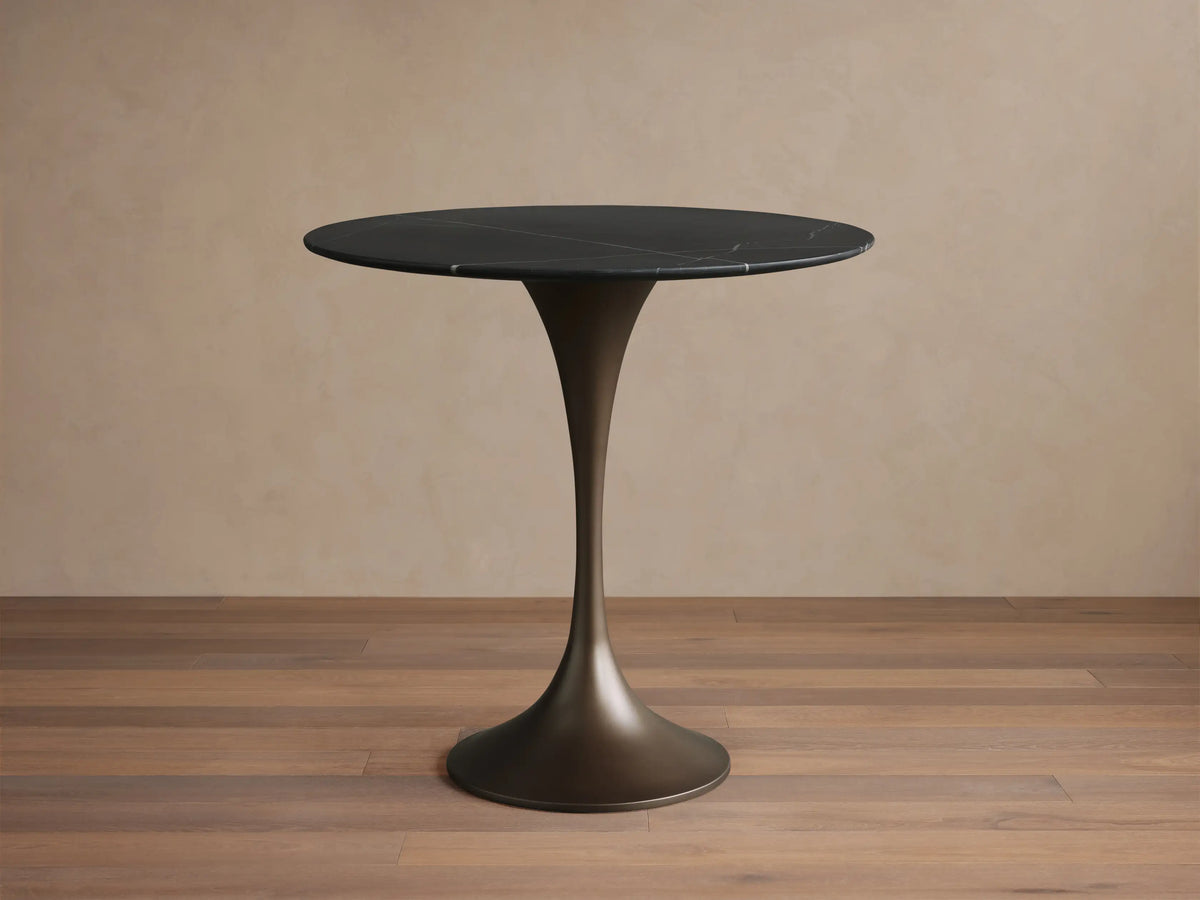 A round black tabletop made of Marquina marble, featuring white veining patterns, set against a neutral background.