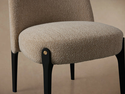 Bottoni Dining Chair, light beige textured upholstery, rounded back, dark black legs with brass tacks, front view.