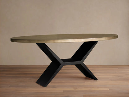 Oval dining table with a brass-toned recycled metal top and a striking black iron Vertex Base, against a neutral wall.