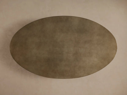 Close-up of Recycled Metal Dining Table. Oval brass-toned, hand-hammered tabletop with butterfly stamp, black Vertex base.