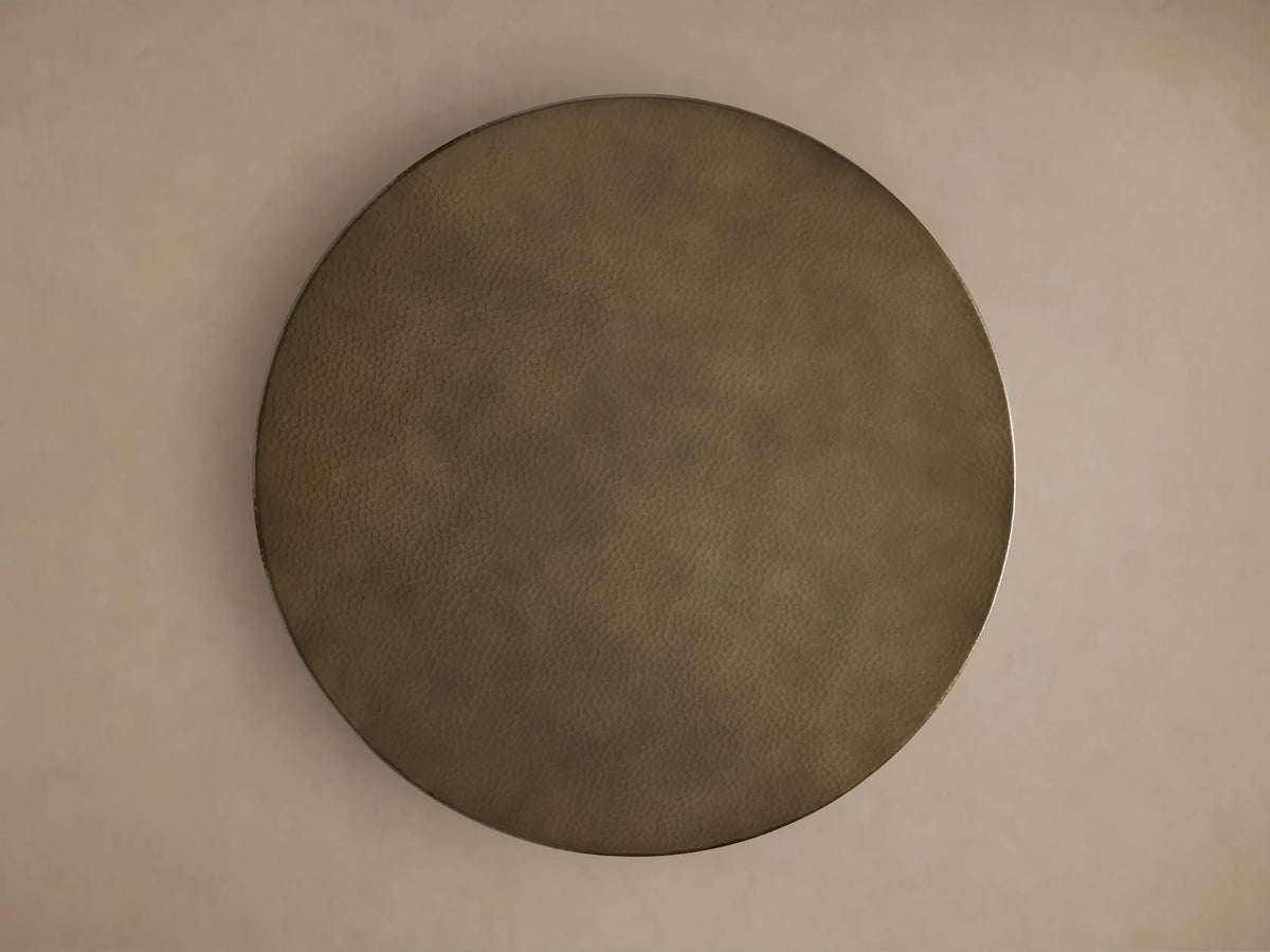 Close-up of Recycled Metal Bistro Table with Wade Base. Round, brass-toned hammered tabletop, polished edge, dark base visible.