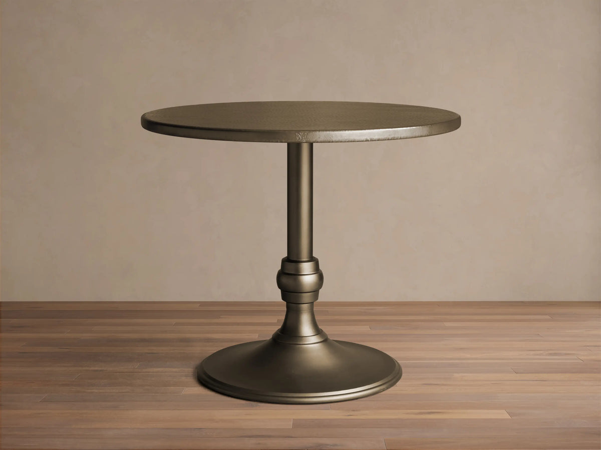 Front view of a brass-finished Recycled Metal Bistro Table with Wade Base, featuring a round top and flared pedestal base.