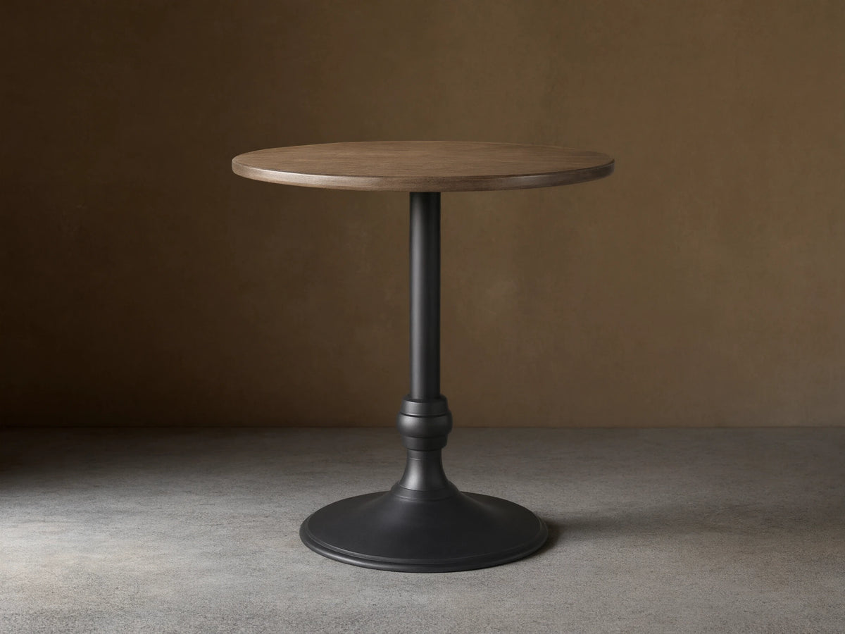 Recycled Metal Counter Table with a round, dark metallic top and a matte black Wade pedestal base on a wood floor.