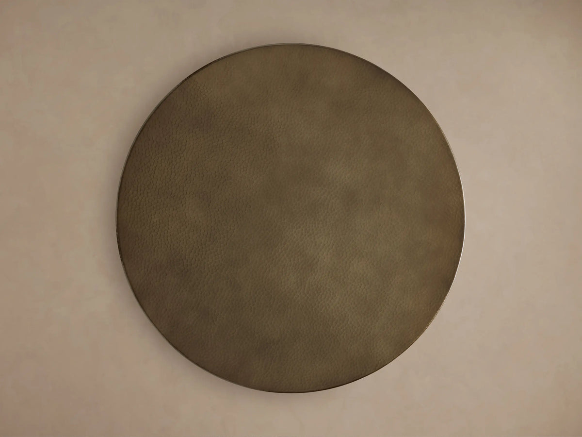 Recycled Metal Bar Table, close-up of round, hammered brass-finished tabletop. Textured surface reflects light, showing intricate detail.