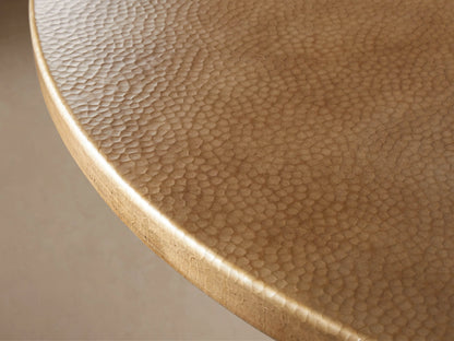 Round brass-finished recycled metal bistro tabletop, hammered texture, viewed from above on a light beige background.